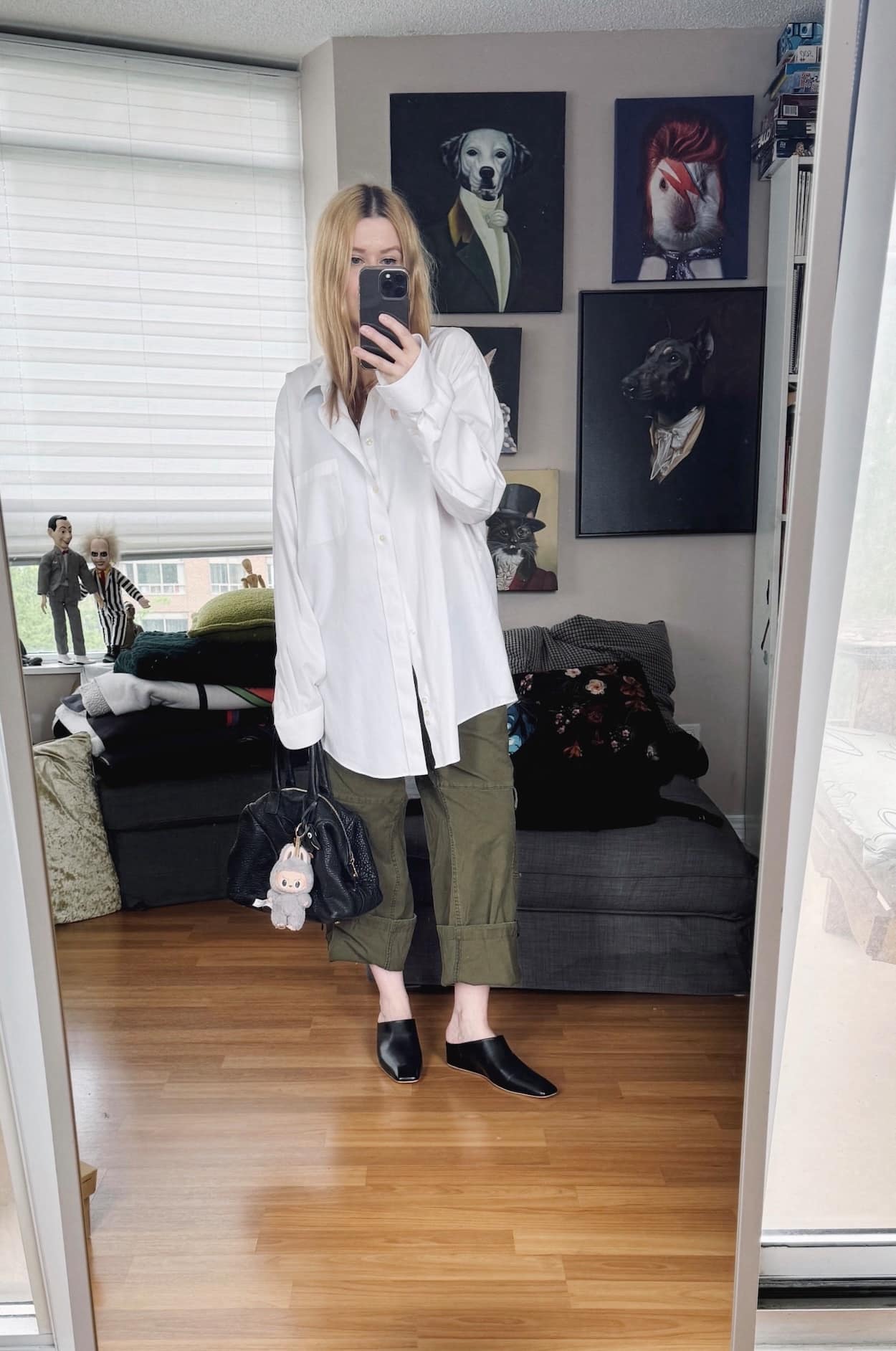 Sara of livelovesara is standing in front of a mirror taking a photo of her outfit. She is wearing a button up, cuffed cargo pants, black mules, and a YSL easy bag.