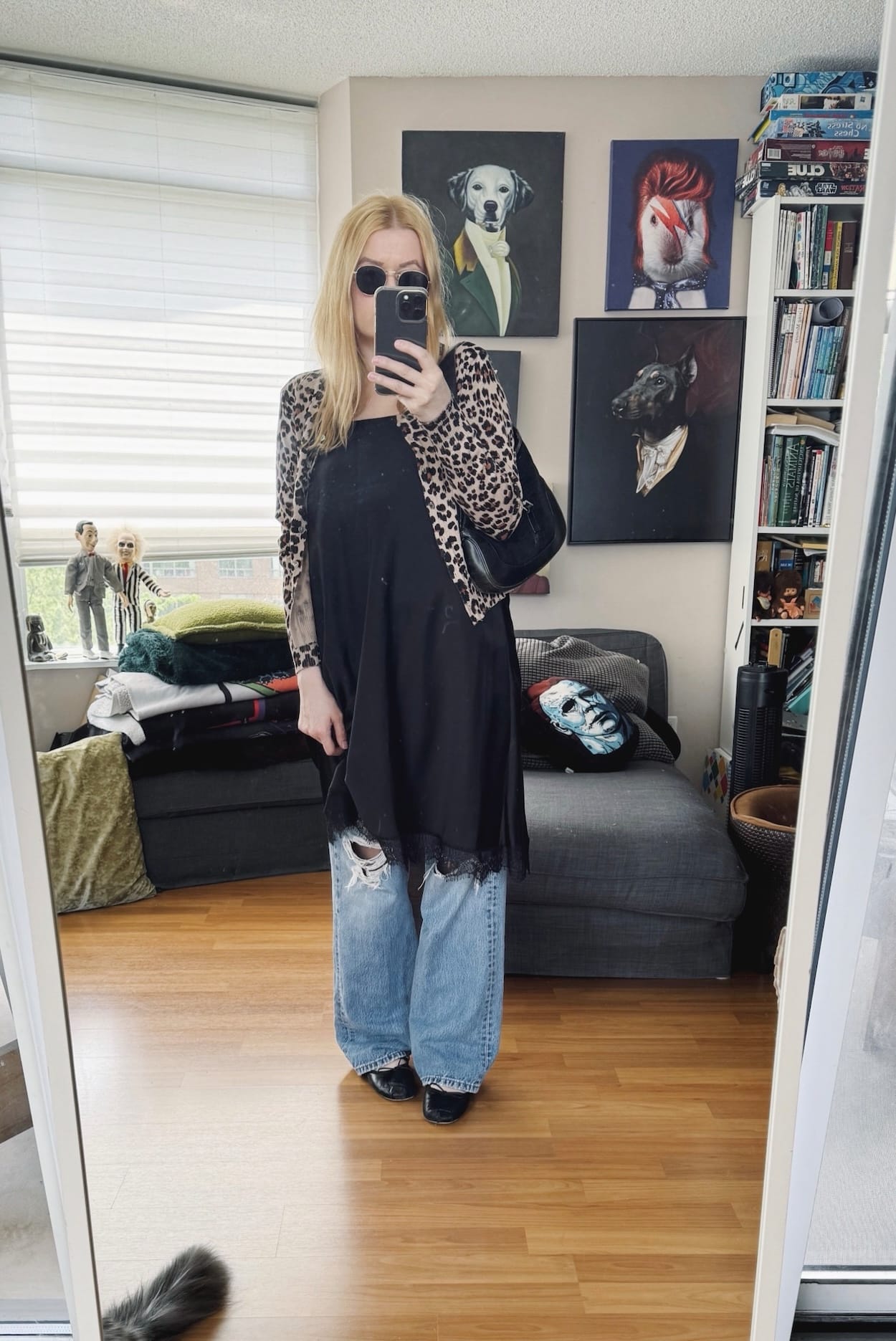 Sara of livelovesara is standing in front of a mirror taking a photo of her outfit. She is wearing a skirt as a top over vintage levis, an animal print cardigan. ballet flats, sunglasses, and a vintage Gucci jackie bag.