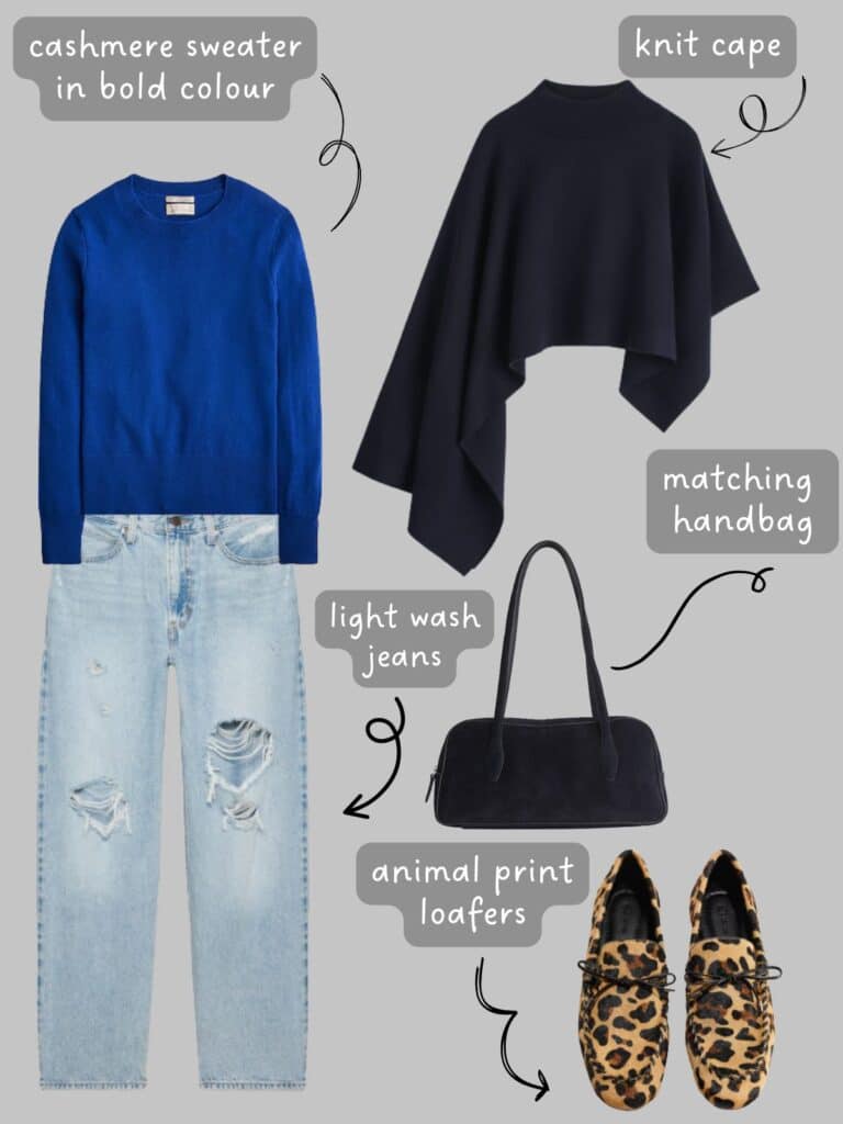 A photo of an outfit of a blue sweater with light wash jeans, a navy knit cape, navy handbag, and animal print loafers.