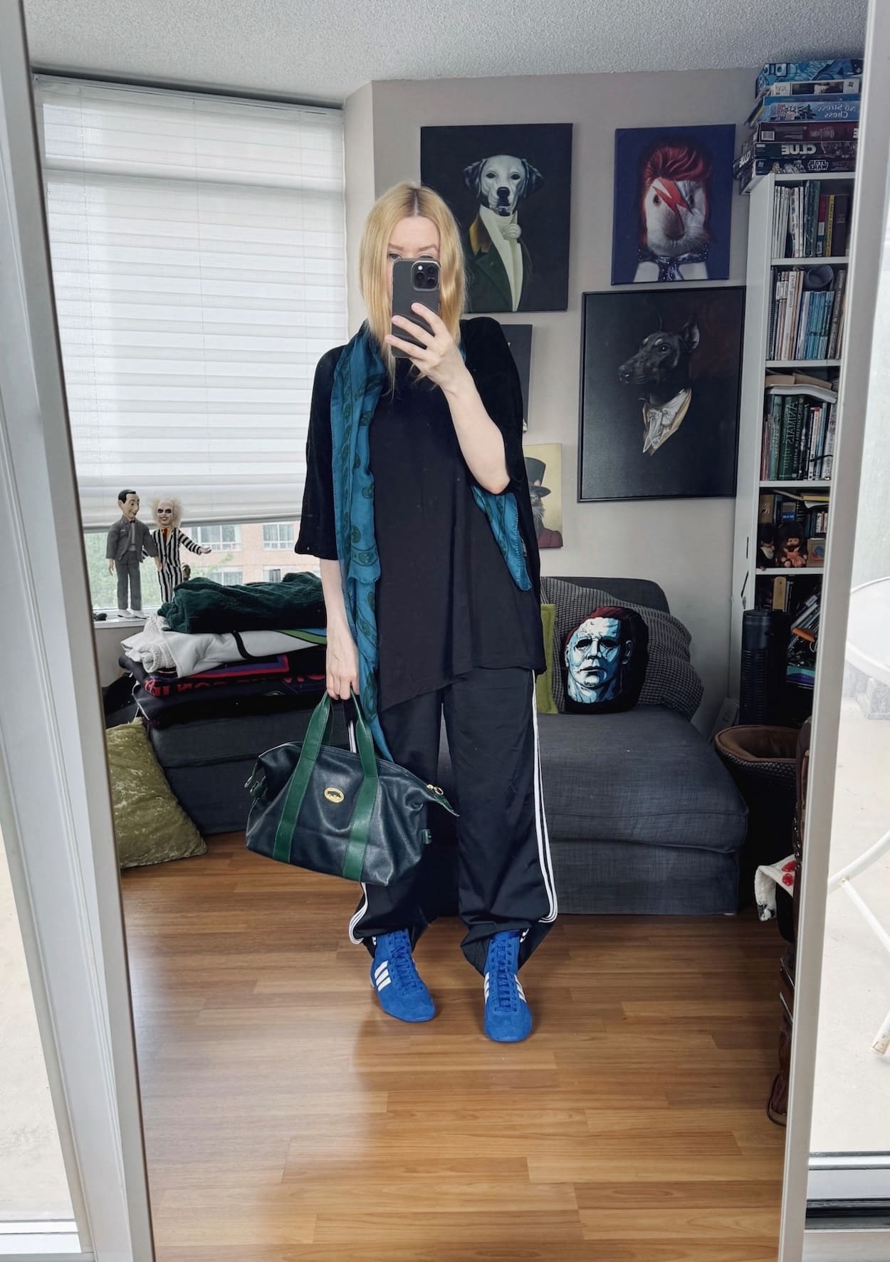 Sara of livelovesara is standing in front of a mirror taking a photo of her outfit. She is wearing an oversized black tee, with Adidas track pants tucked into blue Adidas high sneakers, a blue Alexander McQueen scarf, and a vintage Longchamp bag.