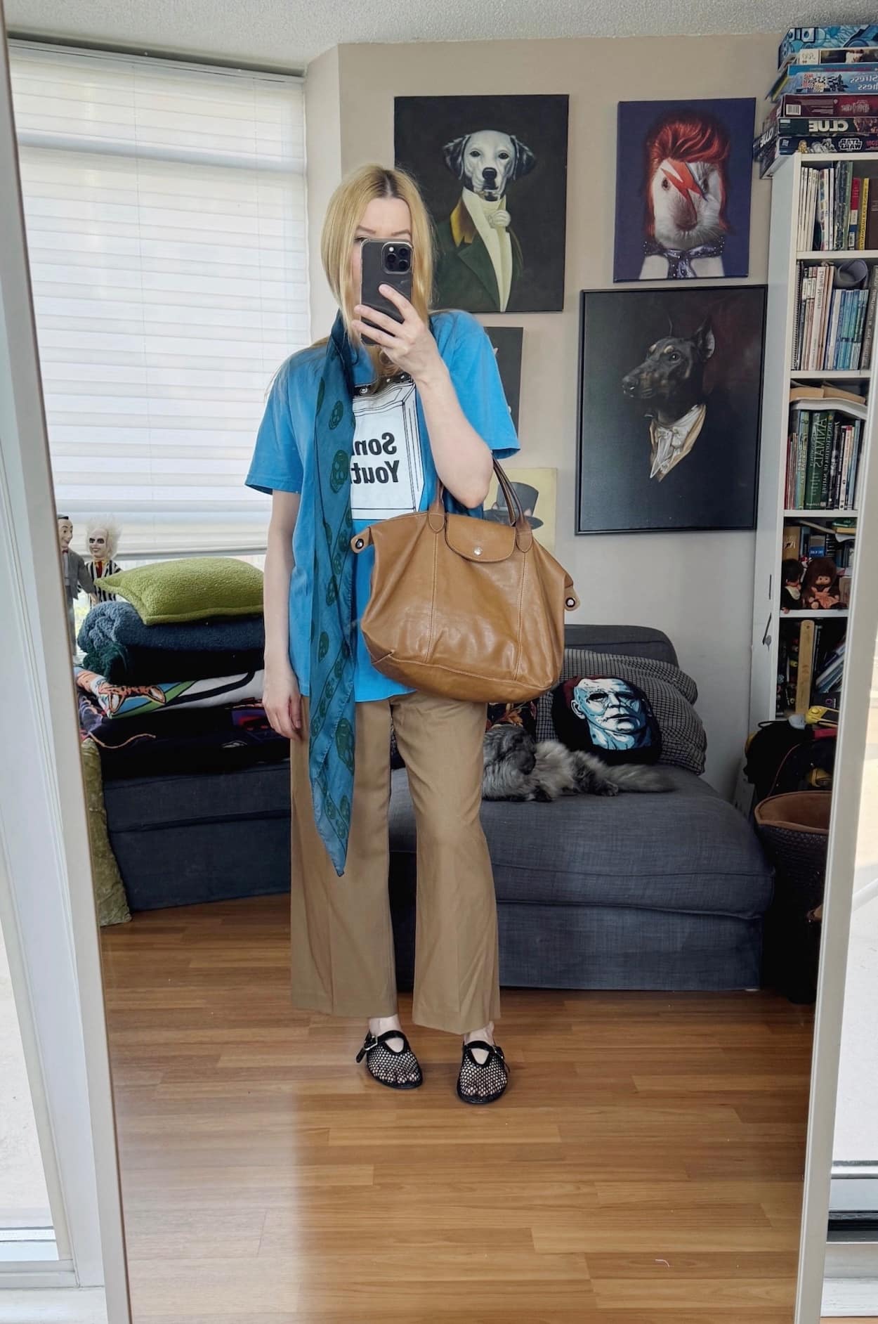 Sara of livelovesara is standing in front of a mirror taking a photo of her outfit. She is wearing a Sonic Youth t-shirt, camel trousers, mesh flats, an Alexander McQueen Scarf, and a Leather Longchamp bag.