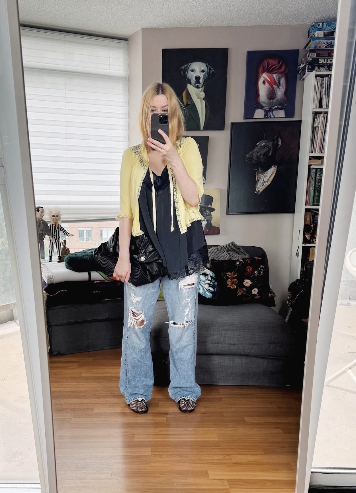 Sara of livelovesara is standing in front of a mirror taking a photo of her outfit. She is wearing a black camisole with a vintage bed jacket, vintage levis, mesh flats, and an issey miyake bao bao bag.