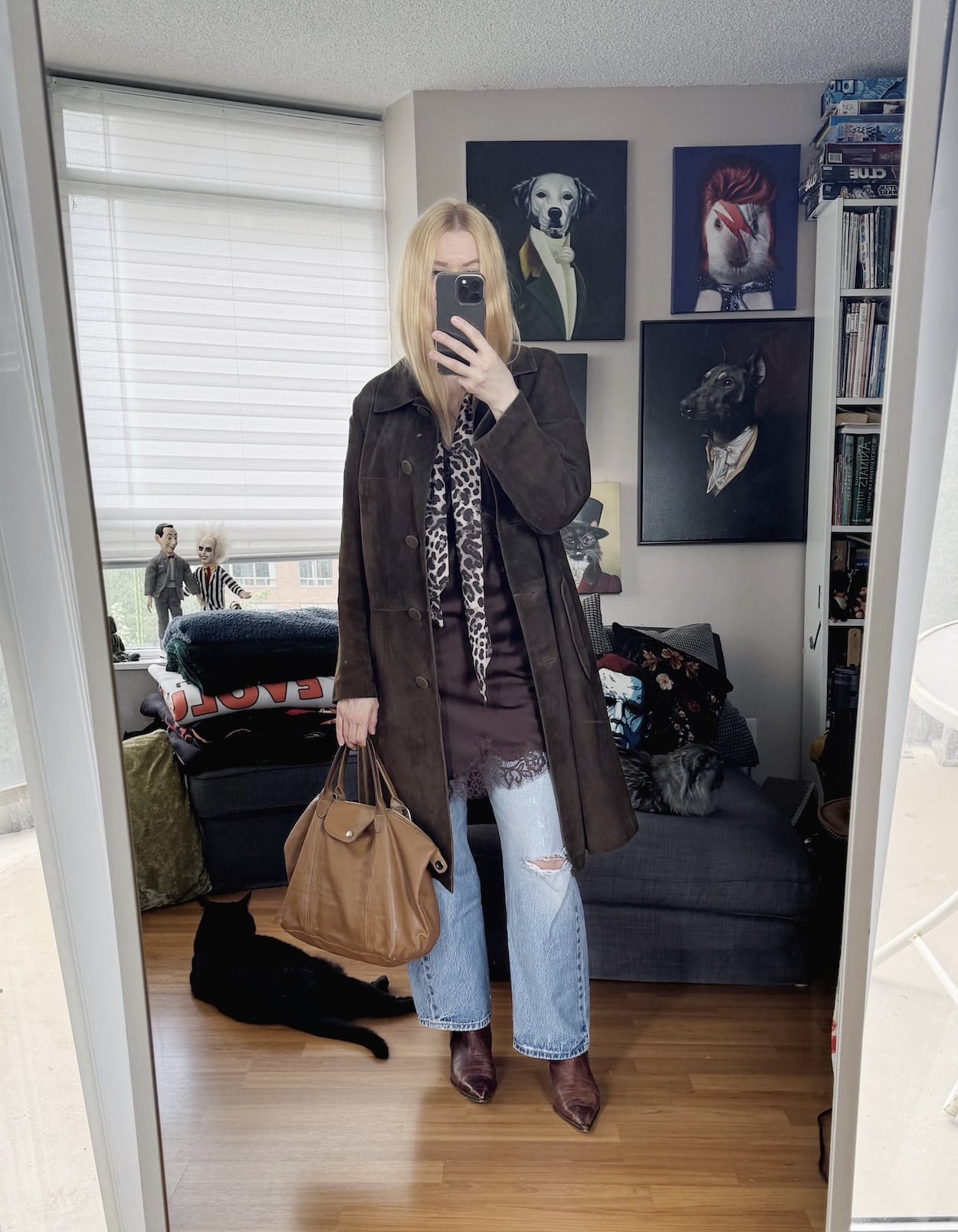 Sara of livelovesara is standing in front of a mirror taking a photo of her outfit. She is wearing a camisole under a vintage suede coat, vintage Levis, brown boots, a skinny scarf, and a brown tote.