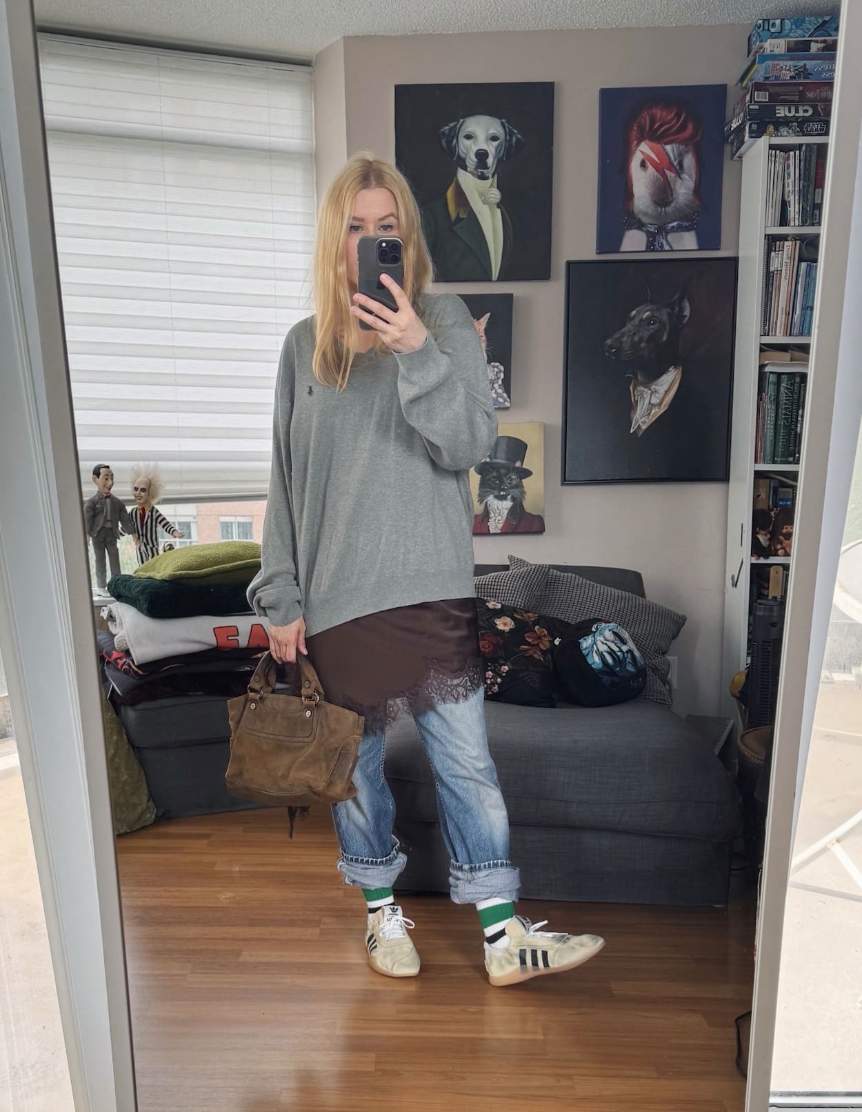 Sara of livelovesara is standing in front of a mirror taking a photo of her outfit. She is wearing a grey sweater over a camisole, vintage levis, adidas x song of the mute sneakers, and a suede celine boogie bag.