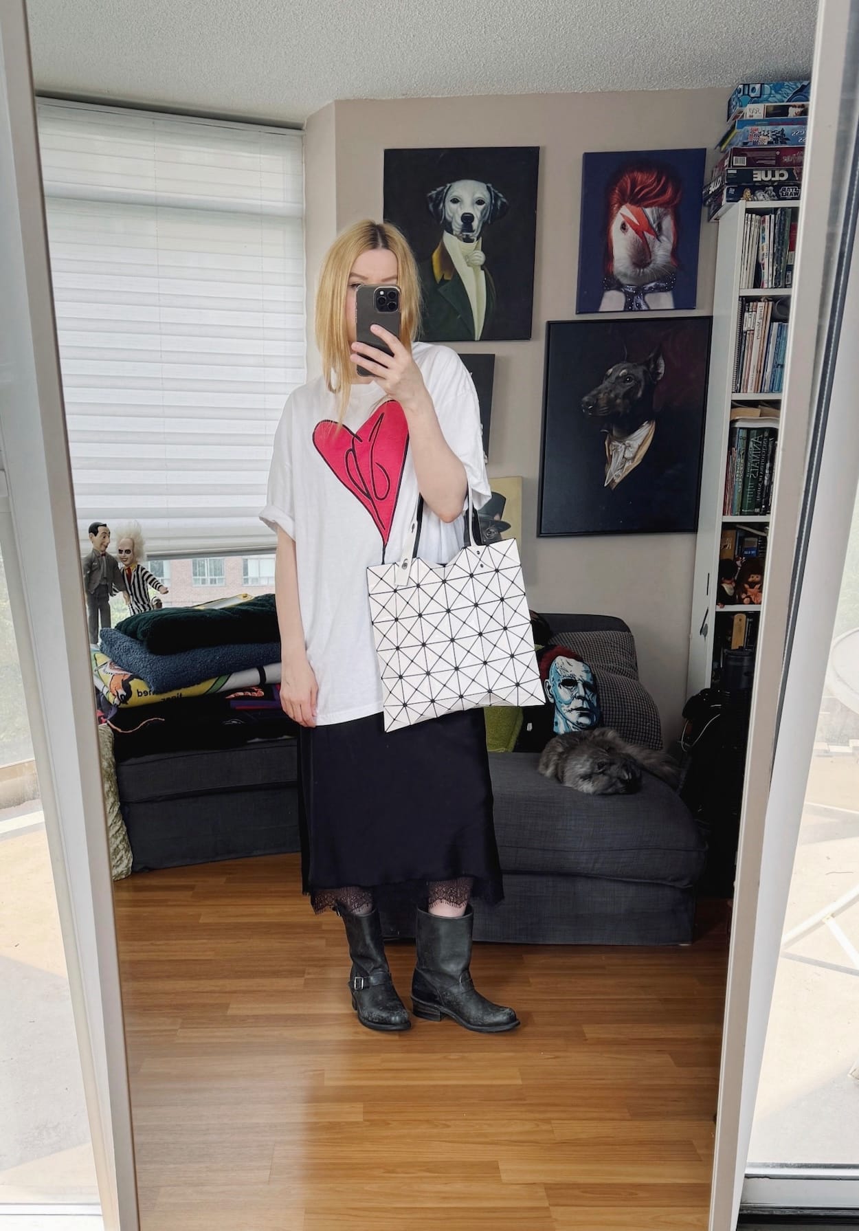 Sara of livelovesara is standing in front of a mirror taking a photo of her outfit. She is wearing a smashing pumkin tee, slip skirt, moto boots, and an Issaey Miyake Bao Bao bag.