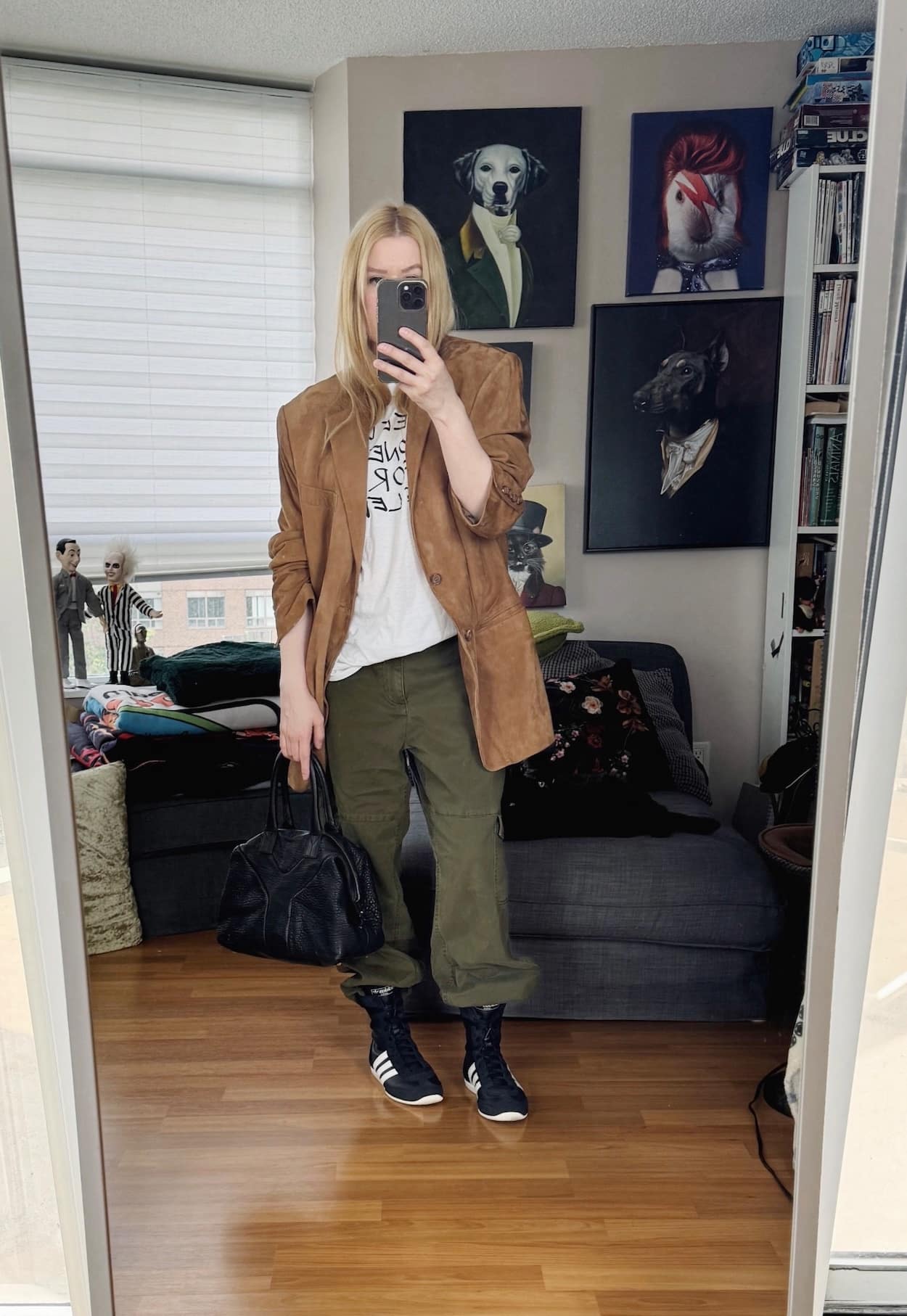Sara of livelovesara is standing in front of a mirror taking a photo of her outfit. She is wearing a white tee under a suede blazer, cargo pants, wrestling sneakers, and a YSL easy bag.