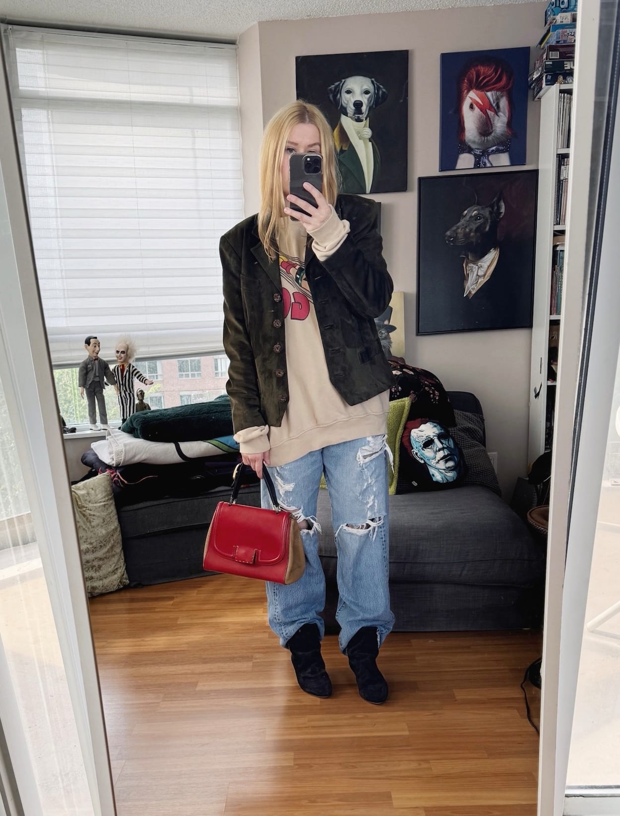 Sara of livelovesara is standing in front of a mirror taking a photo of her outfit. She is wearing an Astro Boy sweatshirt under a vintage suede jacket, vintage Levis, Isabel Marant boots, and a Fendi bag.