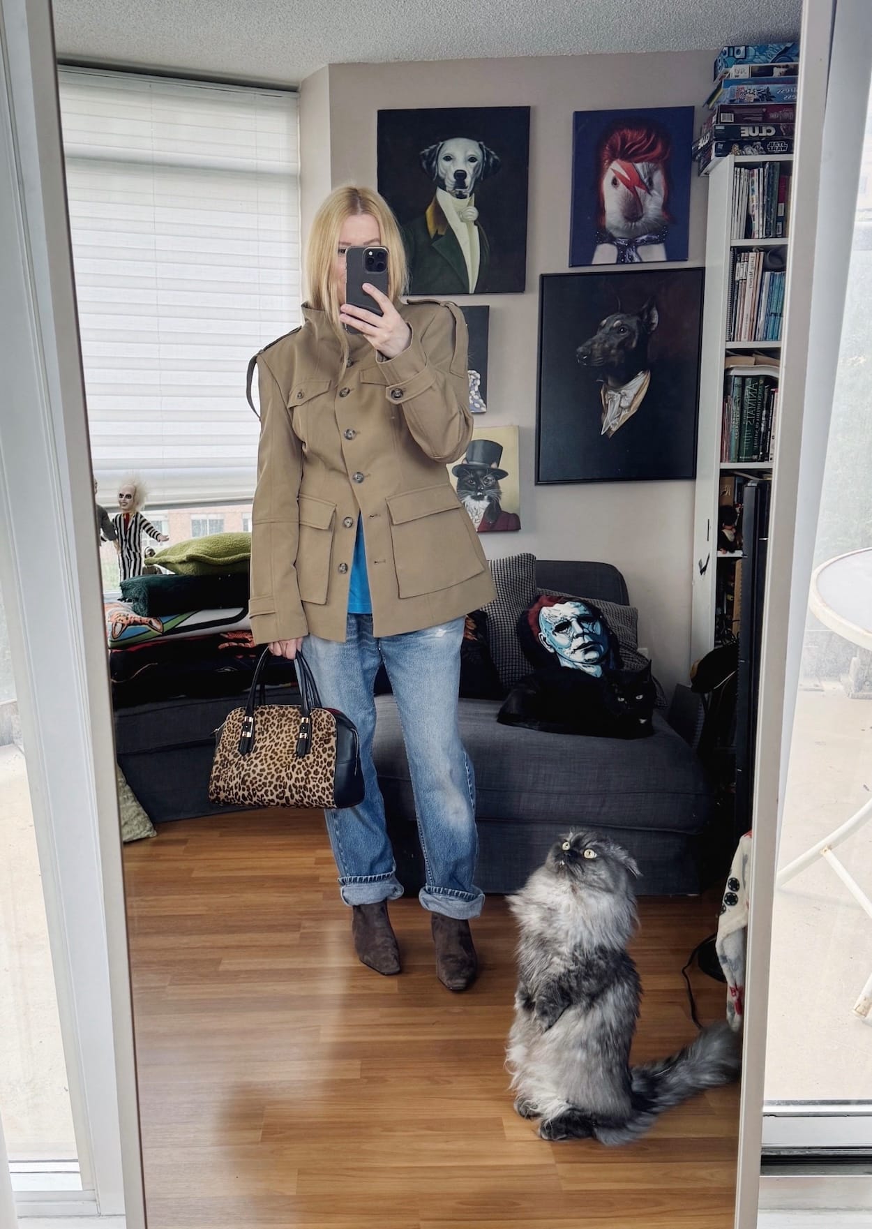 Sara of livelovesara is standing in front of a mirror taking a photo of her outfit. She is wearing a Sonic Youth t-shirt under a military-esque jacket, vintage Levis, brown boots, and an animal print bag.