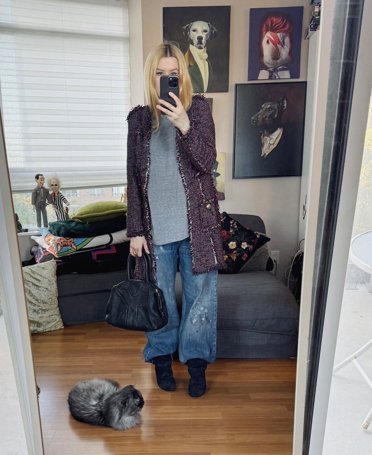 Sara of livelovesara is standing in front of a mirror taking a photo of her outfit. She is wearing a grey tee under a long tweed lady jacket, wide leg jeans, slouchy boots, and is carrying a YSL easy bag.
