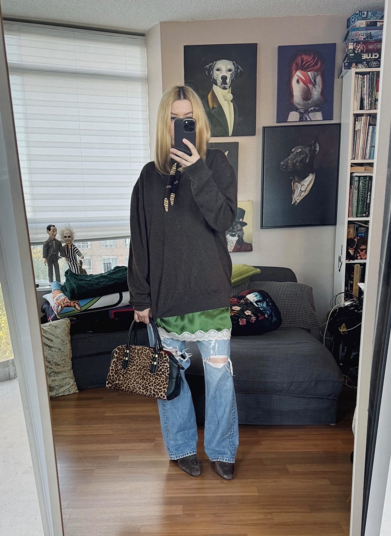 Sara of livelovesara is standing in front of a mirror taking a photo of her outfit. She is wearing a green slip under a brown sweater, with vintage levis, knit bandana scarf, brown boots, and an animal print bag.