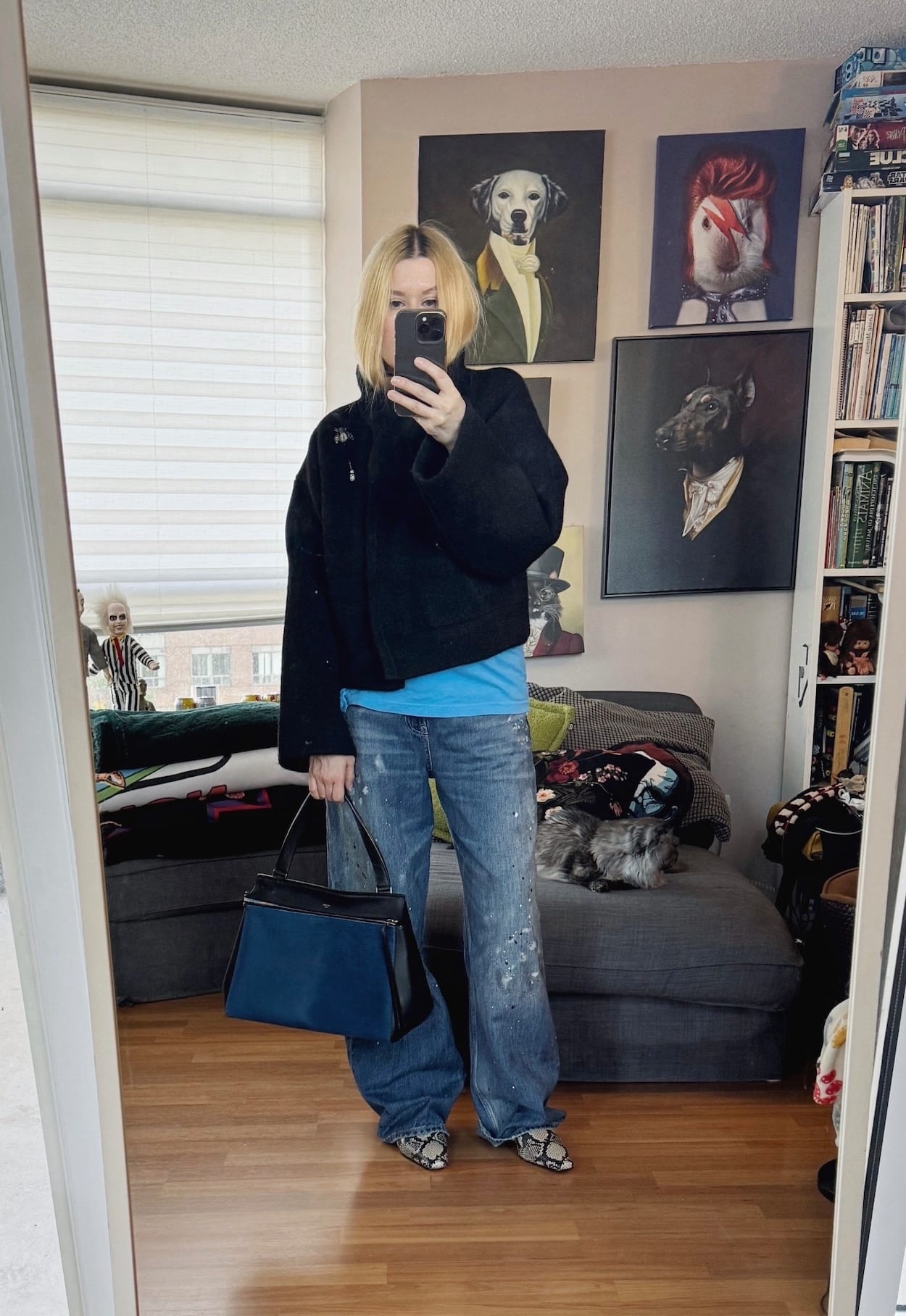 Sara of livelovesara is standing in front of a mirror taking a photo of her outfit. She is wearing a sonic youth t-shirt, a black jacket, paint splatter jeans, snake print boots, and a celine edge bag.