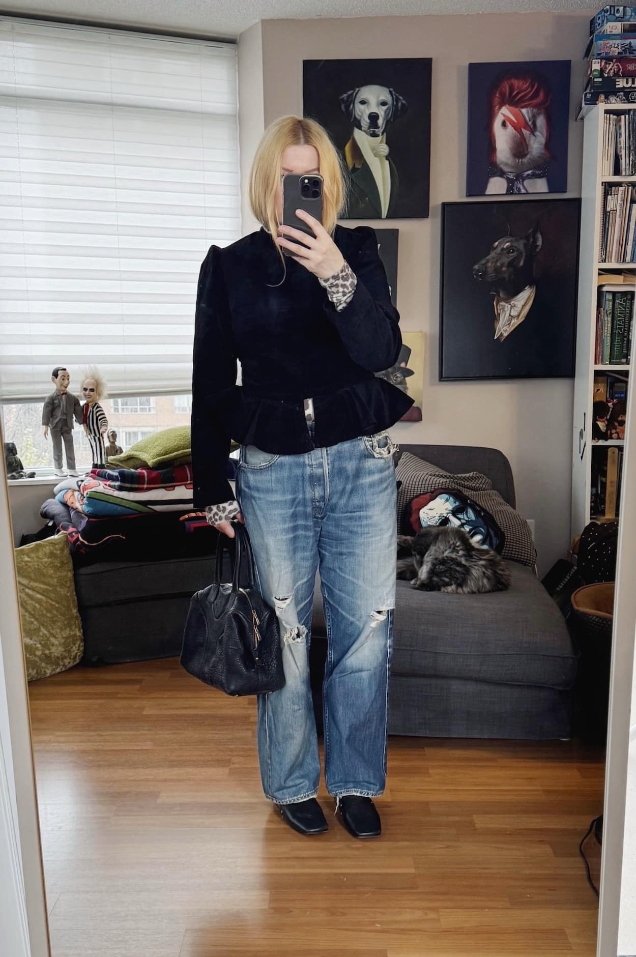 Sara of livelovesara is standing in front of a mirror taking a photo of her outfit. She is wearing a velvet peplum jacket over an animal print turtleneck, vintage Levi's, black booties, and is carrying a black YSL easy bag.