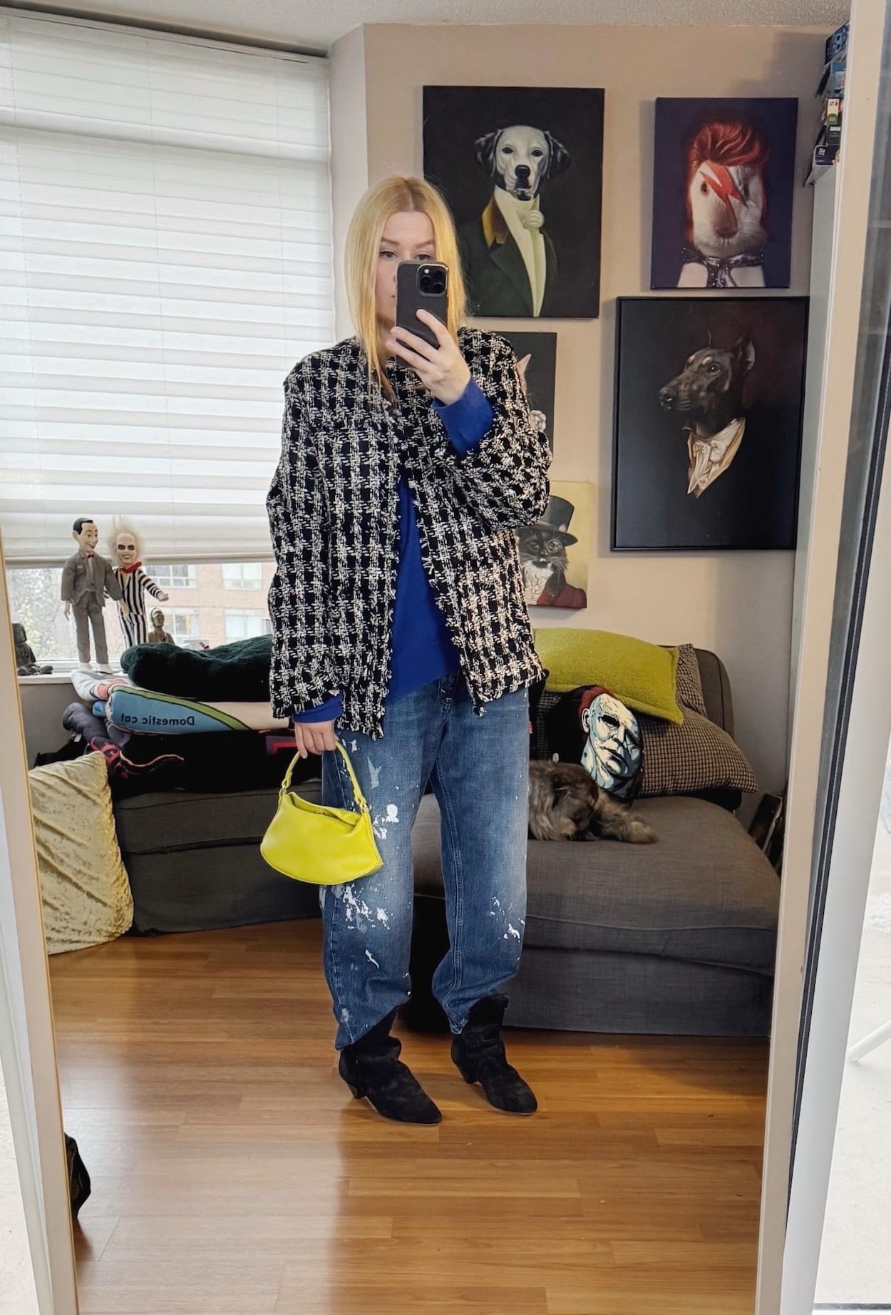 Sara of livelovesara is standing in front of a mirror taking a photo of her outfit. She is wearing a cobalt blue sweater under a tweed jacket, paint splattered jeans, slouchy boots, and is carrying a non yellow bag.