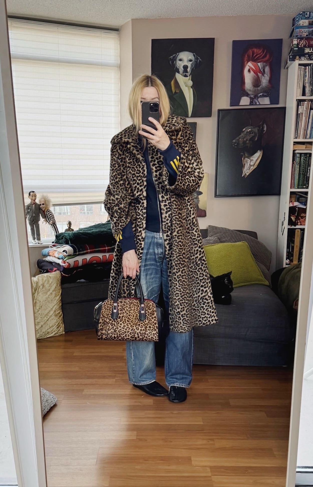 Sara of livelovesara is standing in front of a mirror taking a photo of her outfit. She is wearing a navt blue Adidas track jacket under an vintage leoprad print coat, vintage Levis, flat black boots, and a leopar print bag.