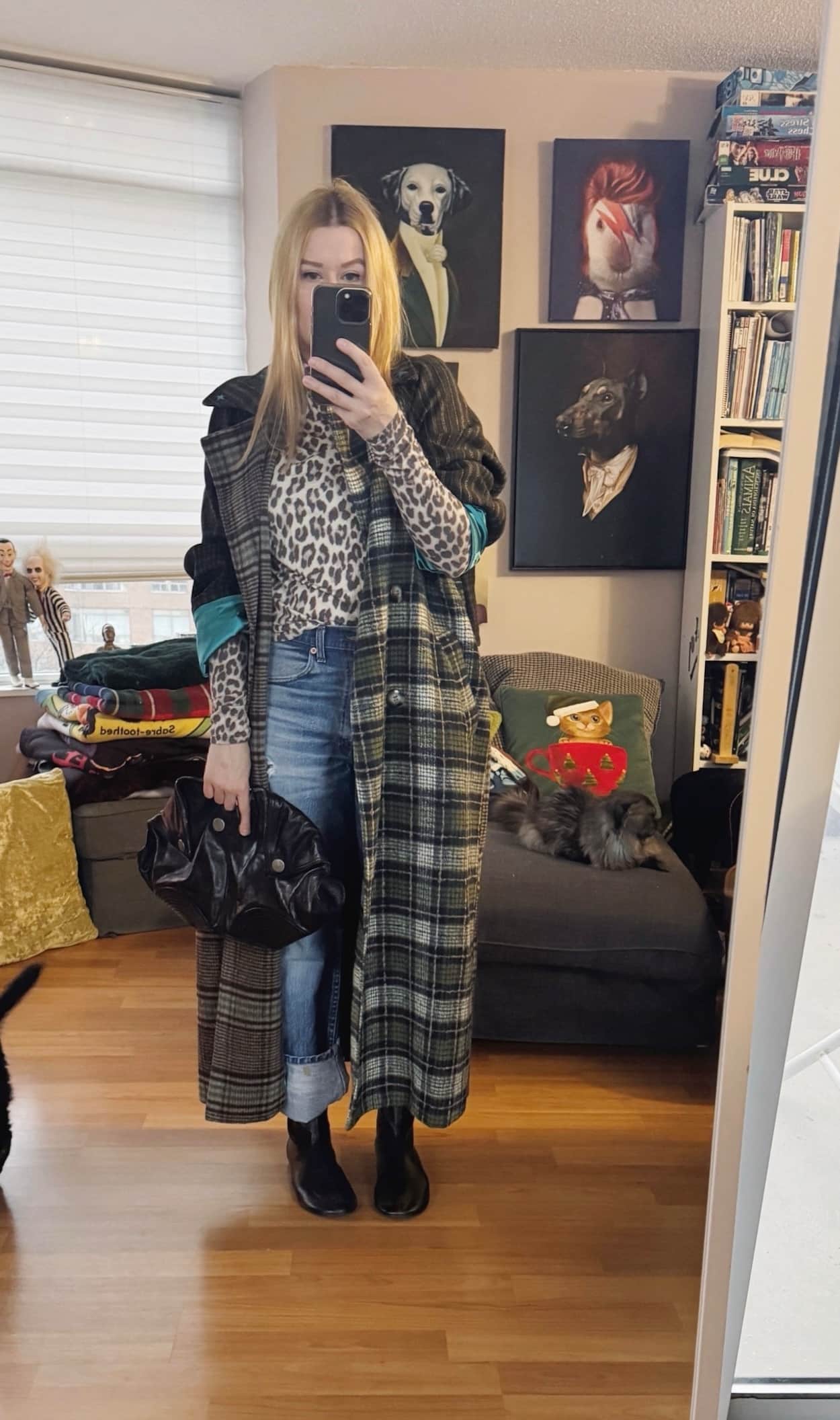 Sara of livelovesara is standing in front of a mirror taking a photo of her outfit. She is wearing a mixed print maxi coat over an animal print turtleneck, vintage Levis, flat black boots, and an Alexander McQueen clutch.