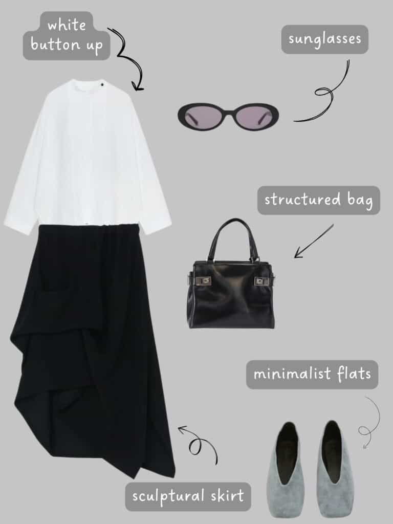A photo of an outfit of a white button up with a black sculptural skirt, black oval sunglasses, a black Ferragamo structured bag, and grey suede flats.