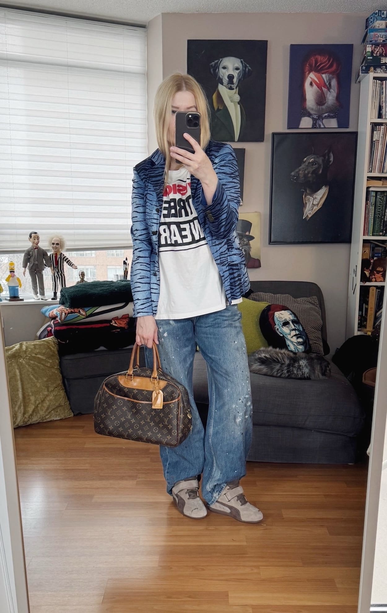 Sara of livelovesara is standing in front of a mirror taking a photo of her outfit. She is wearing a white Vision Streetwear t-shirt under a vintage blue tiger print blazer, paint splatter jeans, Puma wedge sneakers, and a Louis Vuitton vintage deauville bag.