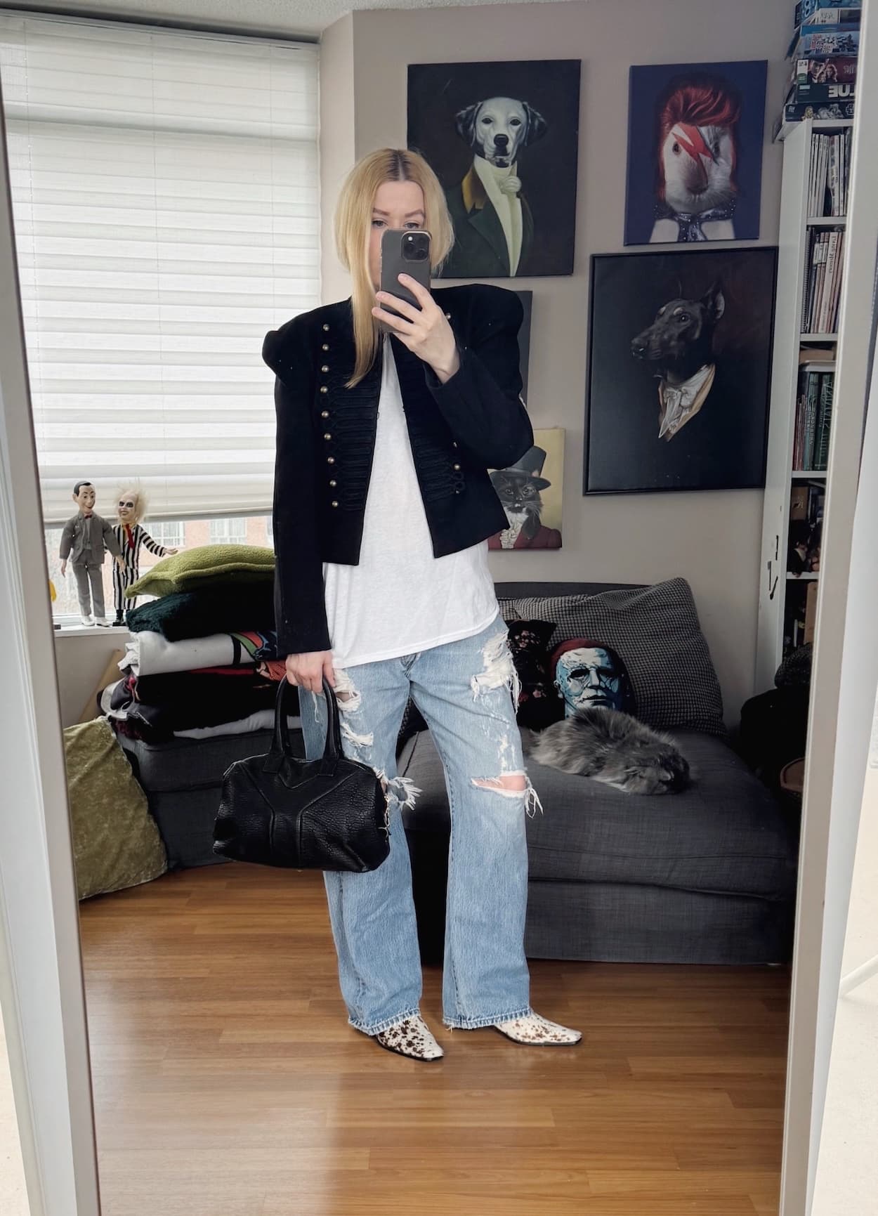 Sara of livelovesara is standing in front of a mirror taking a photo of her outfit. She is wearing a black Napoleon jacket over a white t-shirt, distressed vintage Levi's, deer print heels, and a YSL easy bag.