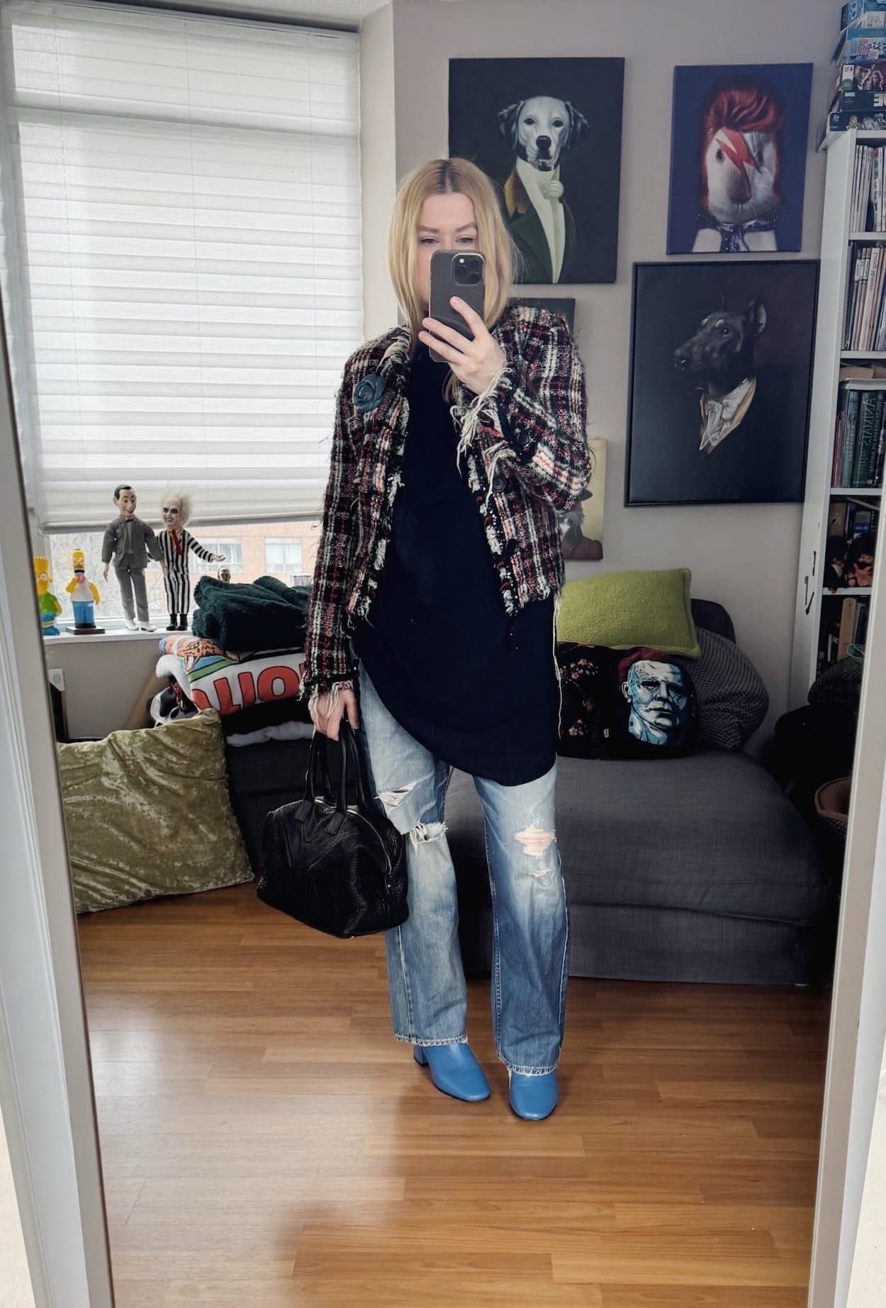 Sara of livelovesara is standing in front of a mirror taking a photo of her outfit. She is wearing a black knit tunic over distressed vintage levi's, a vintage tweed jacket, flower brooch, blue boots, and a ysl easy bag.