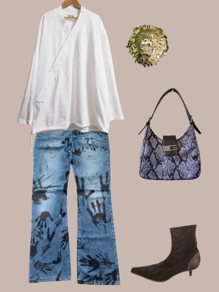 A photo of an outfit of a white crossover top with jeans that have black painted handprints on them. A large lion head brooch, purple snake print bag, and brown kitten heel boots.