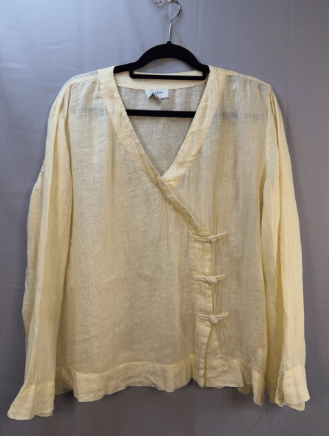 cream linen blouse with wrap front and frog closures.