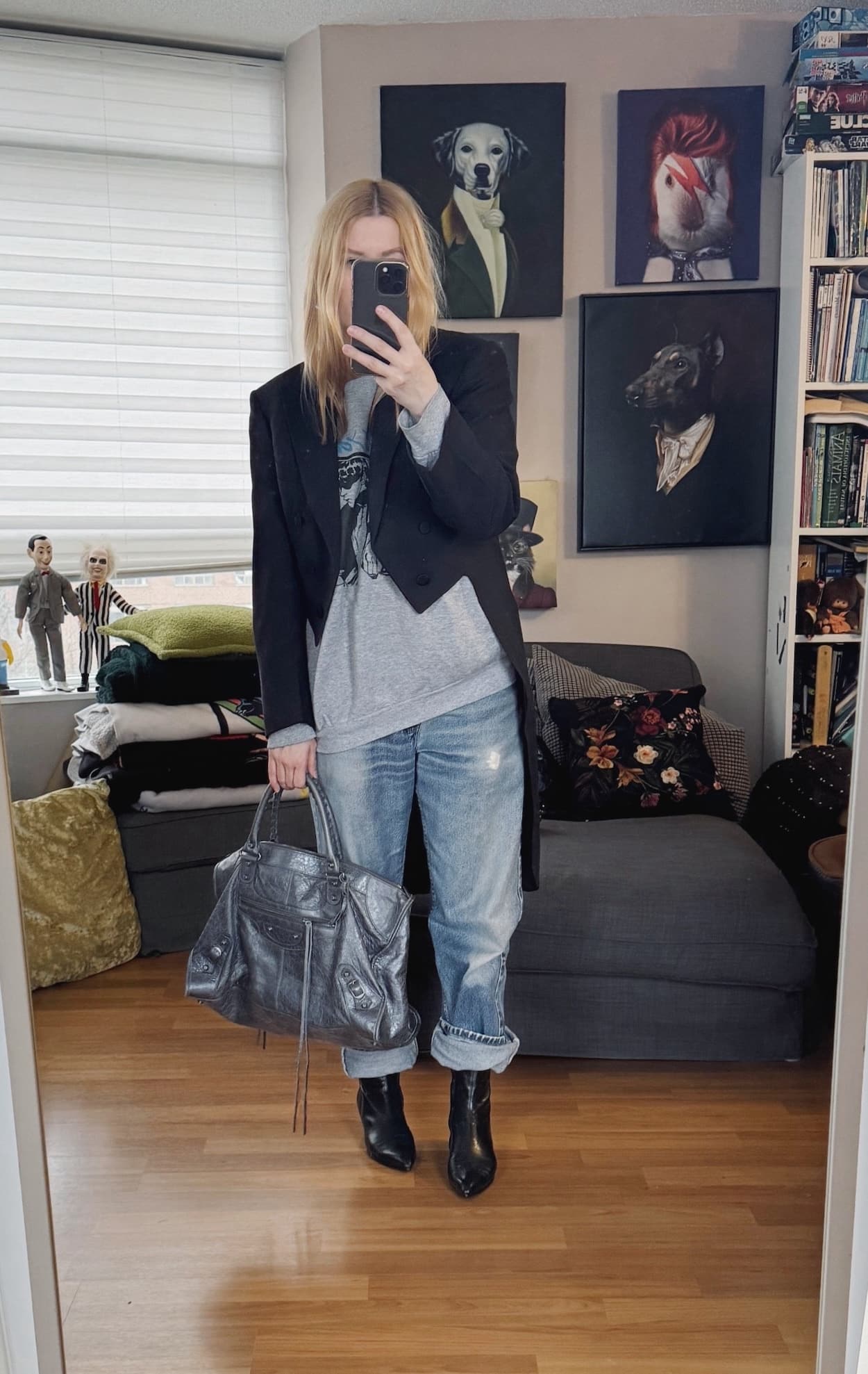 Sara of livelovesara is standing in front of a mirror taking a photo of her outfit. She is wearing a Sonic Youth swetashirt under a vintage tailcoat, vintage Levis, vintage black kitten heel boots, and a grey Balenciaga work bag.