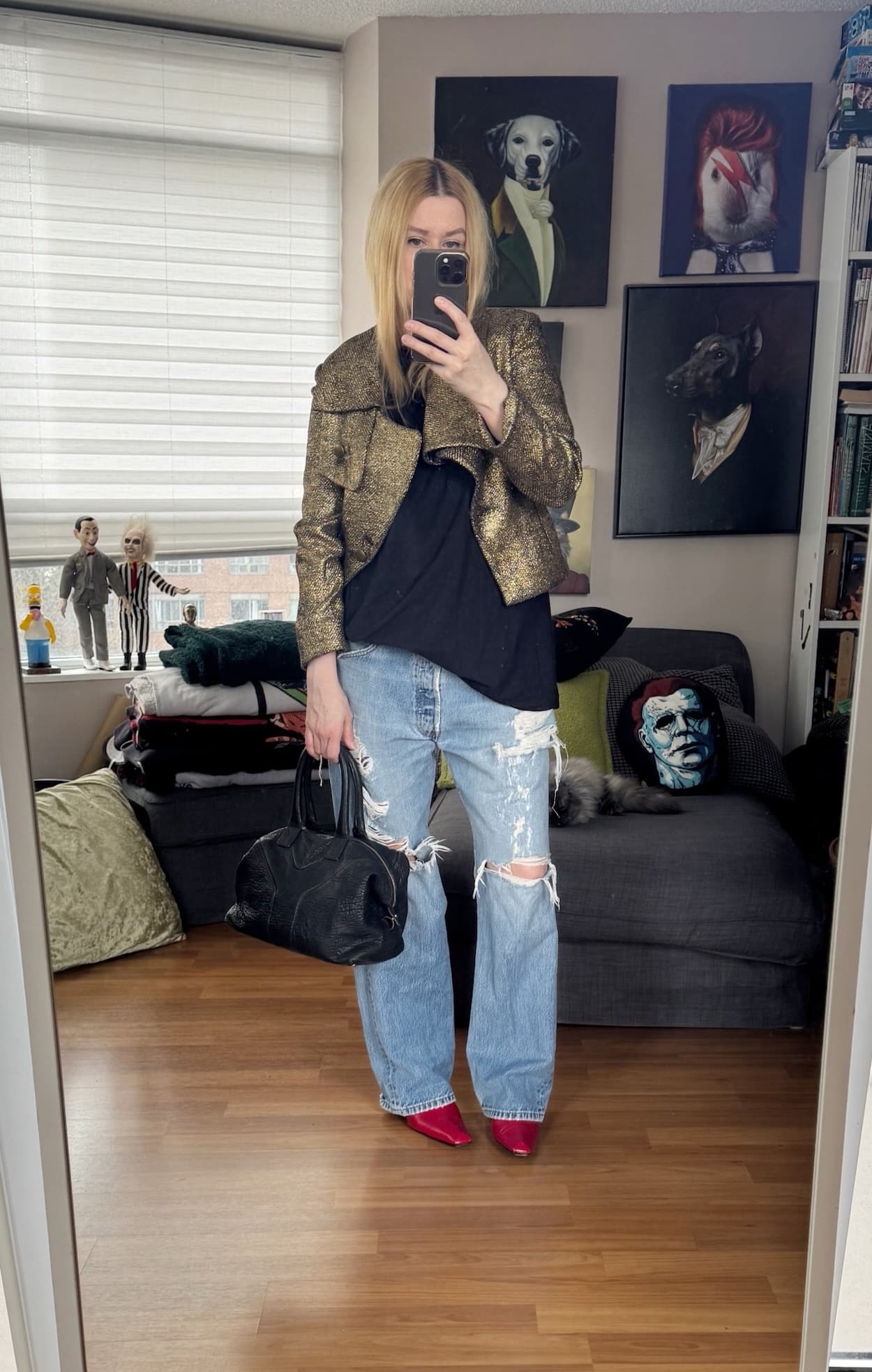 Sara of livelovesara is standing in front of a mirror taking a photo of her outfit. She is wearing a black tee under a cold cropped jacket, vintage levis with distressing, red kitten heel boots, and a black YSL easy bag.