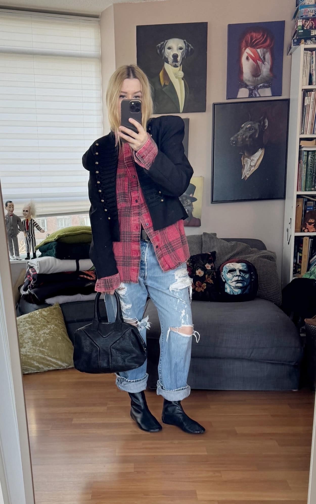 Sara of livelovesara is standing in front of a mirror taking a photo of her outfit. She is wearing a red plaid shirt under a Napoleon jacket with vintage distressed jeans, black flat boots, and a ysl easy bag.