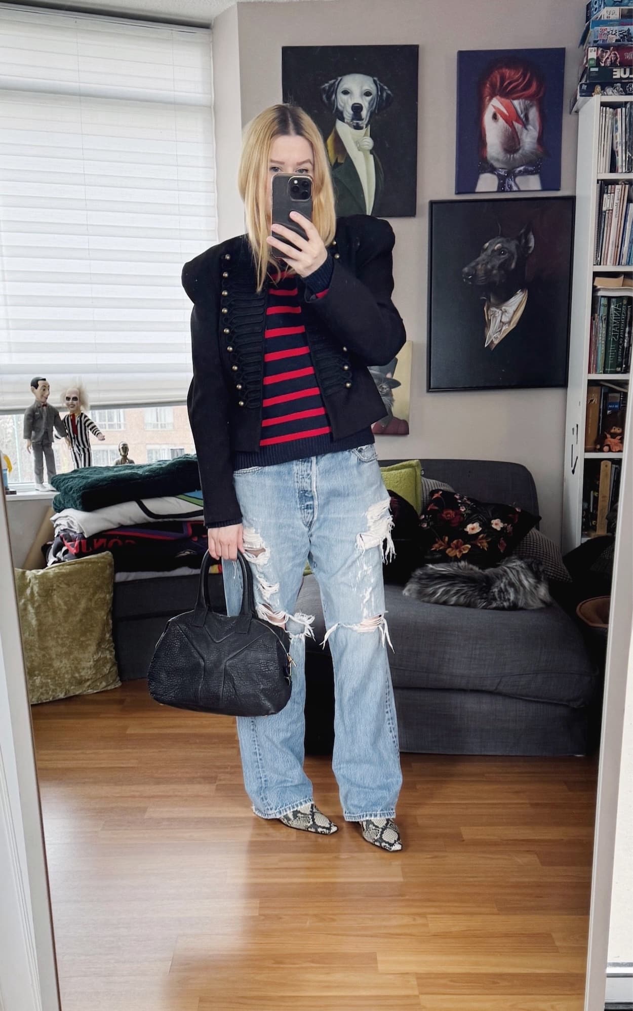 Sara of livelovesara is standing in front of a mirror taking a photo of her outfit. She is wearing a red and navy striped sweater under a black Napoleon jacket, vintage levis, snake print boots, and a ysl easy bag.