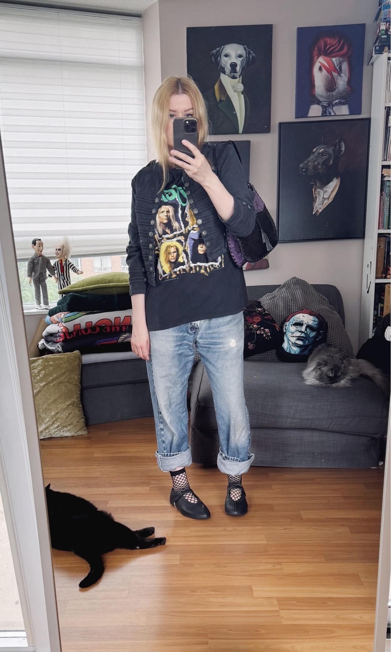 Sara of livelovesara is standing in front of a mirror taking a photo of her outfit. She is wearing a vintage Poison band tee with a grey Napoleon jacket, vintage Levi's, fishnet socks, black mary jane sneakerinas, and a vintage purple and black leather snake print bag.