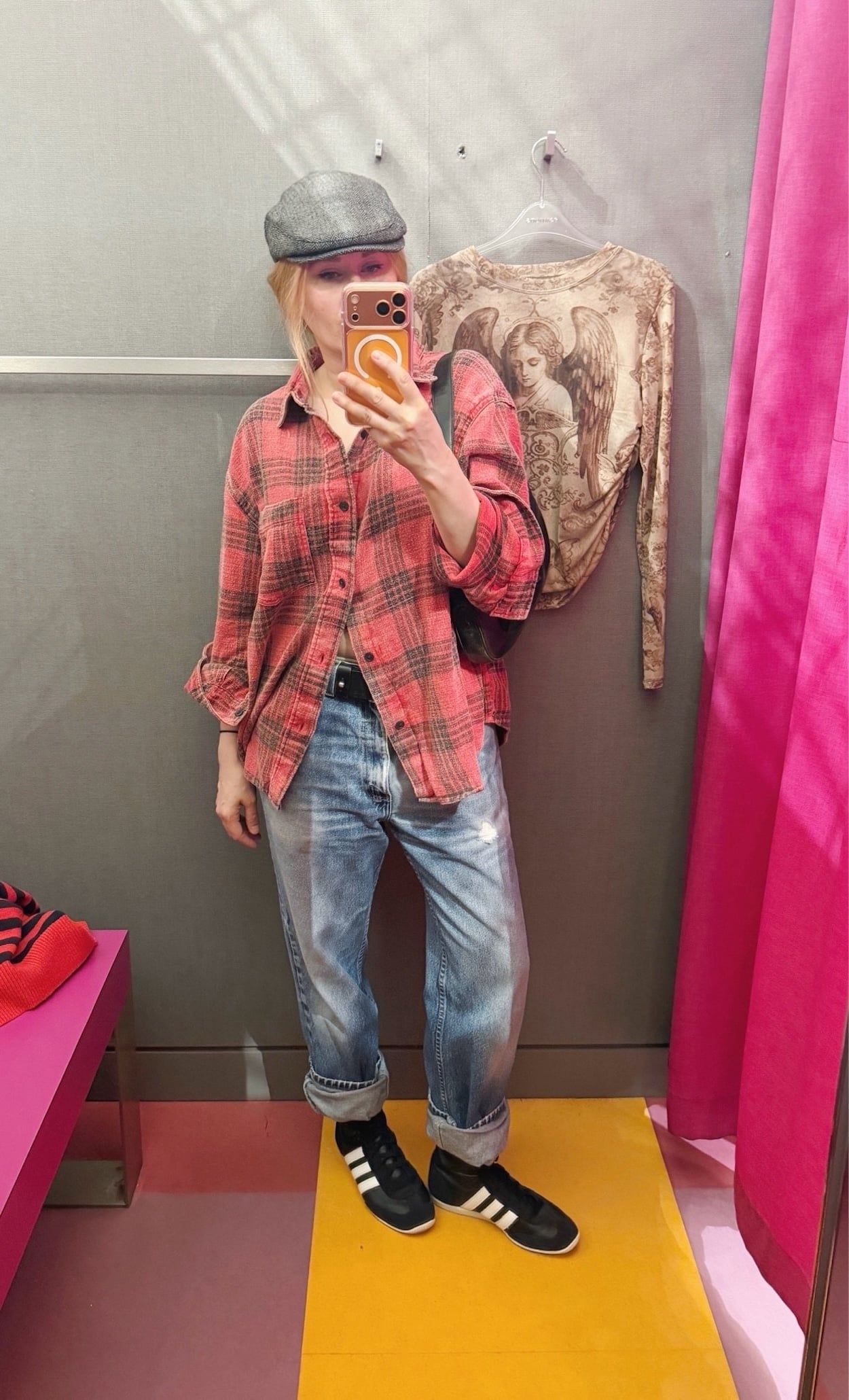 Sara of livelovesara is standing in front of a mirror taking a photo of her outfit. She is wearing a red plaid shirt with vintage levis rolled athte ankle, a studded belt, grey driving cap, and a vintage Gucci Jackie bag.