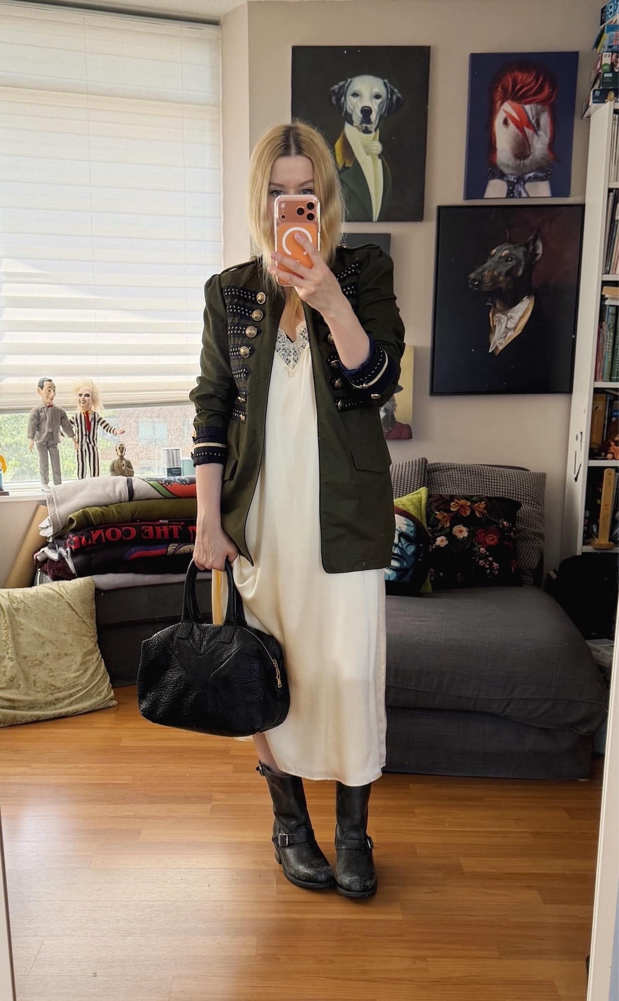 Sara of livelovesara is standing in front of a mirror taking a photo of her outfit. She is wearing a cream silk slip dress, with a green Napoleon jacket, Frye engineer boots, and a YSL Easy bag.