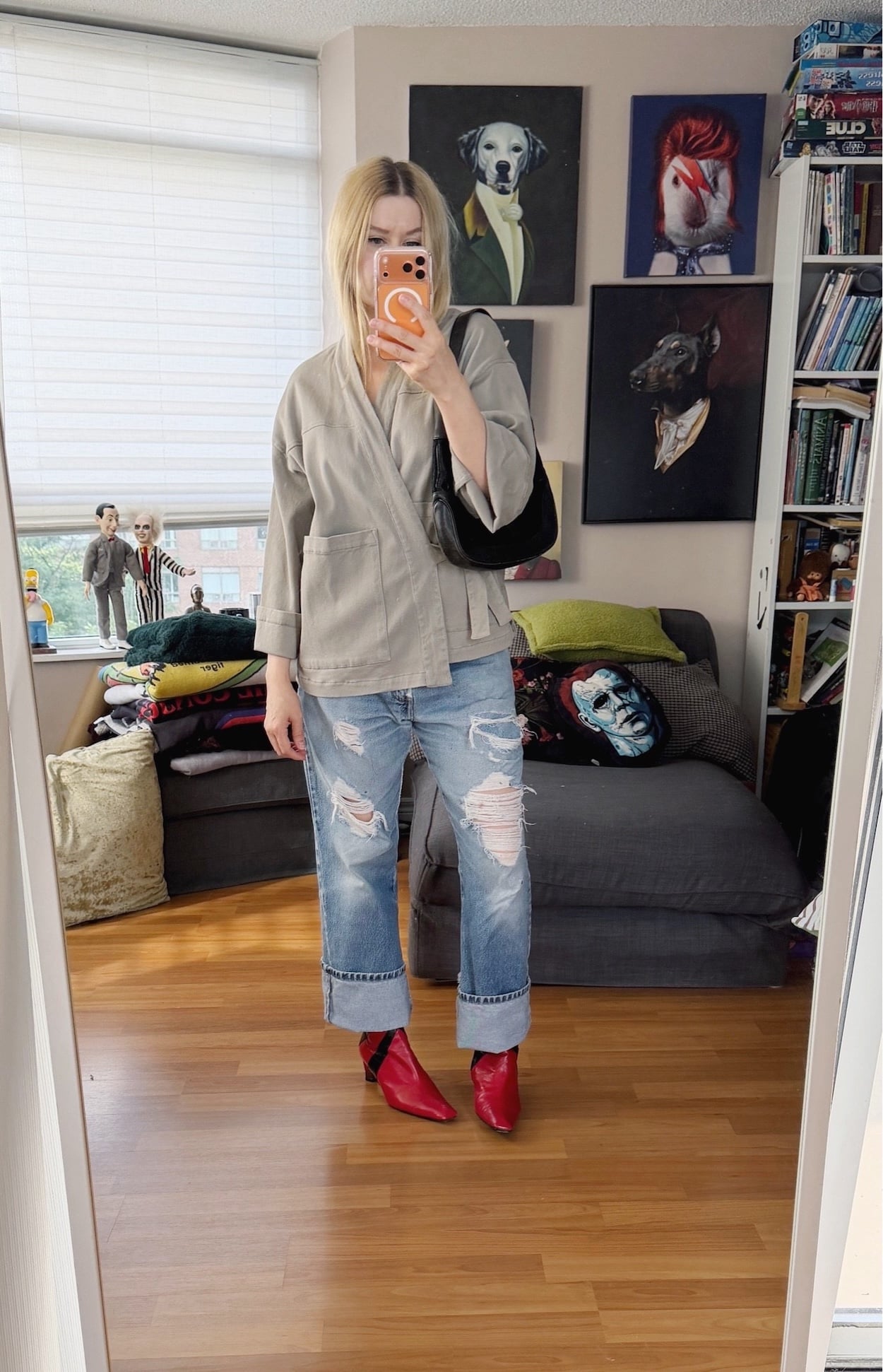 Sara of livelovesara is standing in front of a mirror taking a photo of her outfit. She is wearing a light grey kimono style wrap shirt with vintgae Levis, red vintage boots, and is carrying a black vintage Gucci bag.