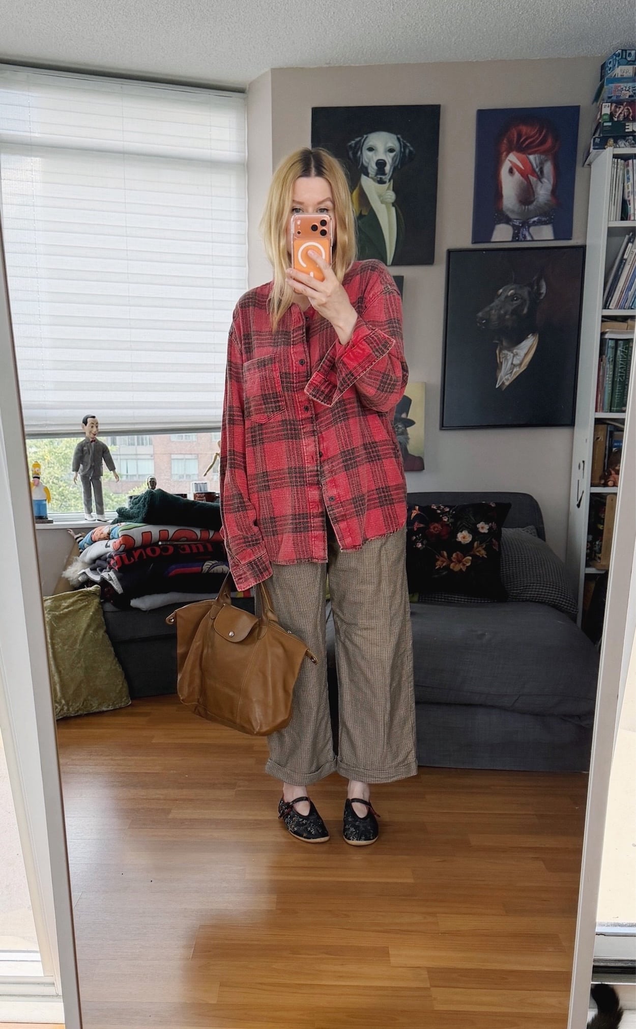 Sara of livelovesara is standing in front of a mirror taking a photo of her outfit. She is wearing a red plaid shirt with vintage brown, check trousers, vintage Adidas ballet flats, and a leather Longchamp bag.
