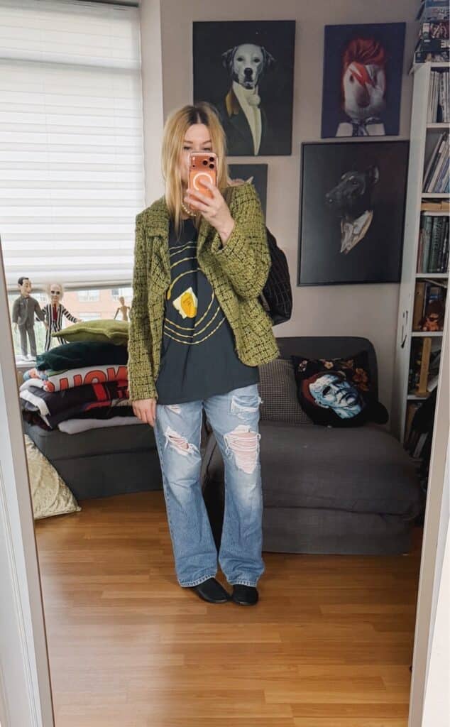 Sara of livelovesara is standing in front of a mirror taking a photo of her outfit. She is wearing a Tori Amos t-shirt under a vintage, green tweed jacket, distressed vintage Levis, flat black boots, and is carrying a Chanel shoulder bag.