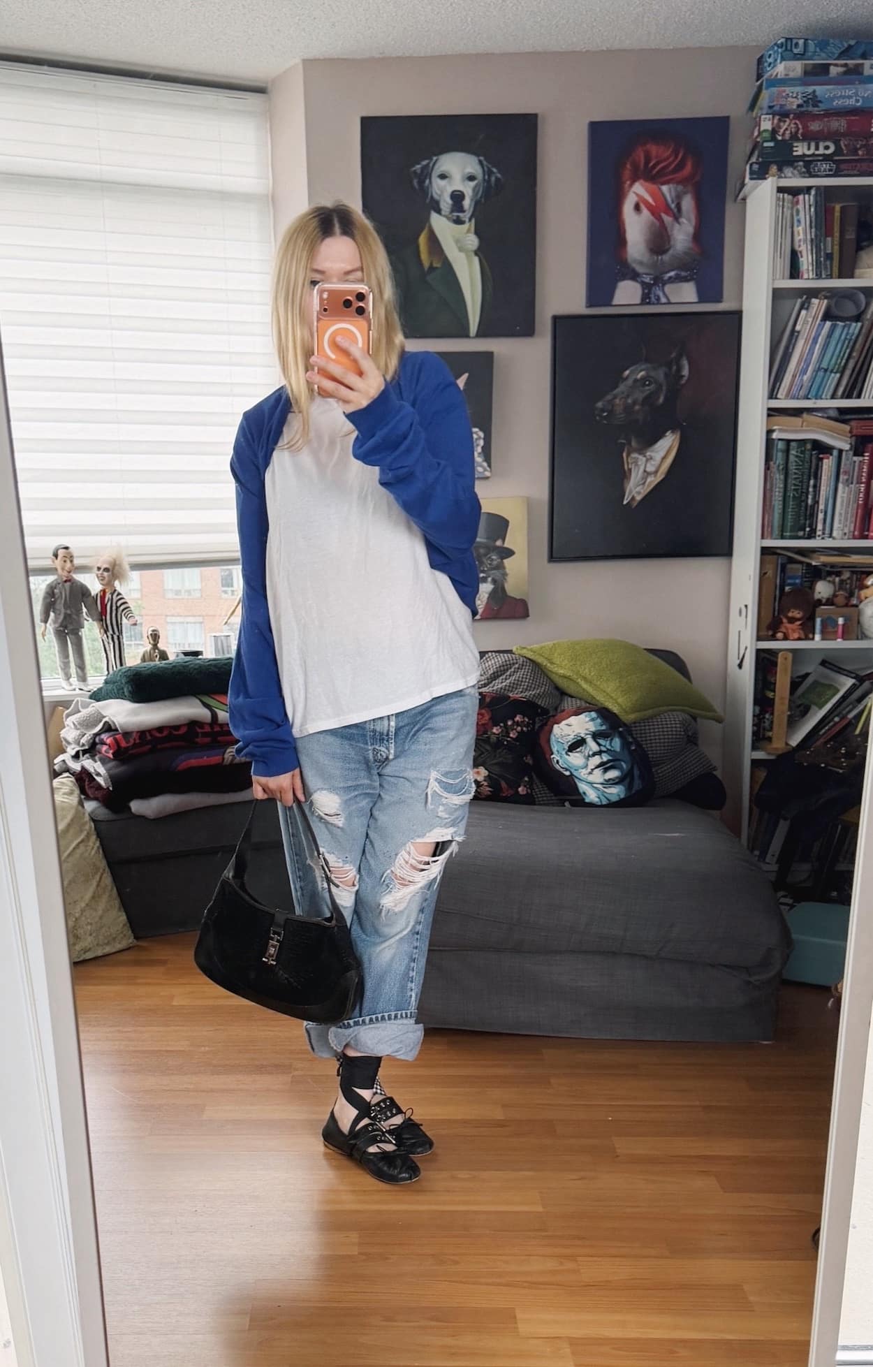 Sara of livelovesara is standing in front of a mirror taking a photo of her outfit. She is wearing a white Hanes t-shirt with a blue sweater worn as a shrug, vintage levis that are cuffed, Miu Miu flats, and is carrying a vintage Gucci Jackie bag.