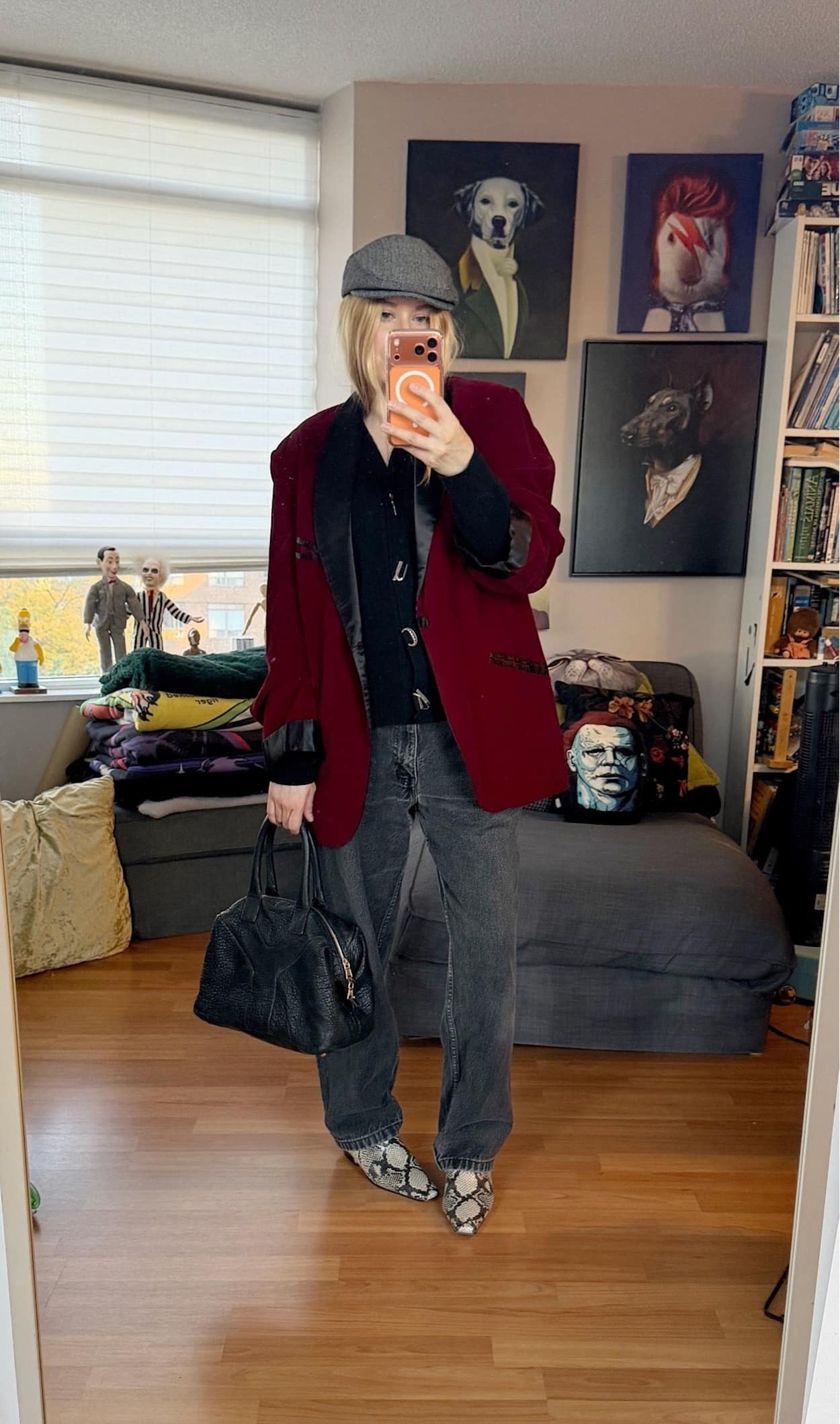 Sara of livelovesara is standing in front of a mirror taking a photo of her outfit. She is wearing a Hades Wool cardigan under a burgundy velvet smoking jacket, black vintage Levis. a grey herringbone Brixton cap, snake print boots, and a YSL easy bag.