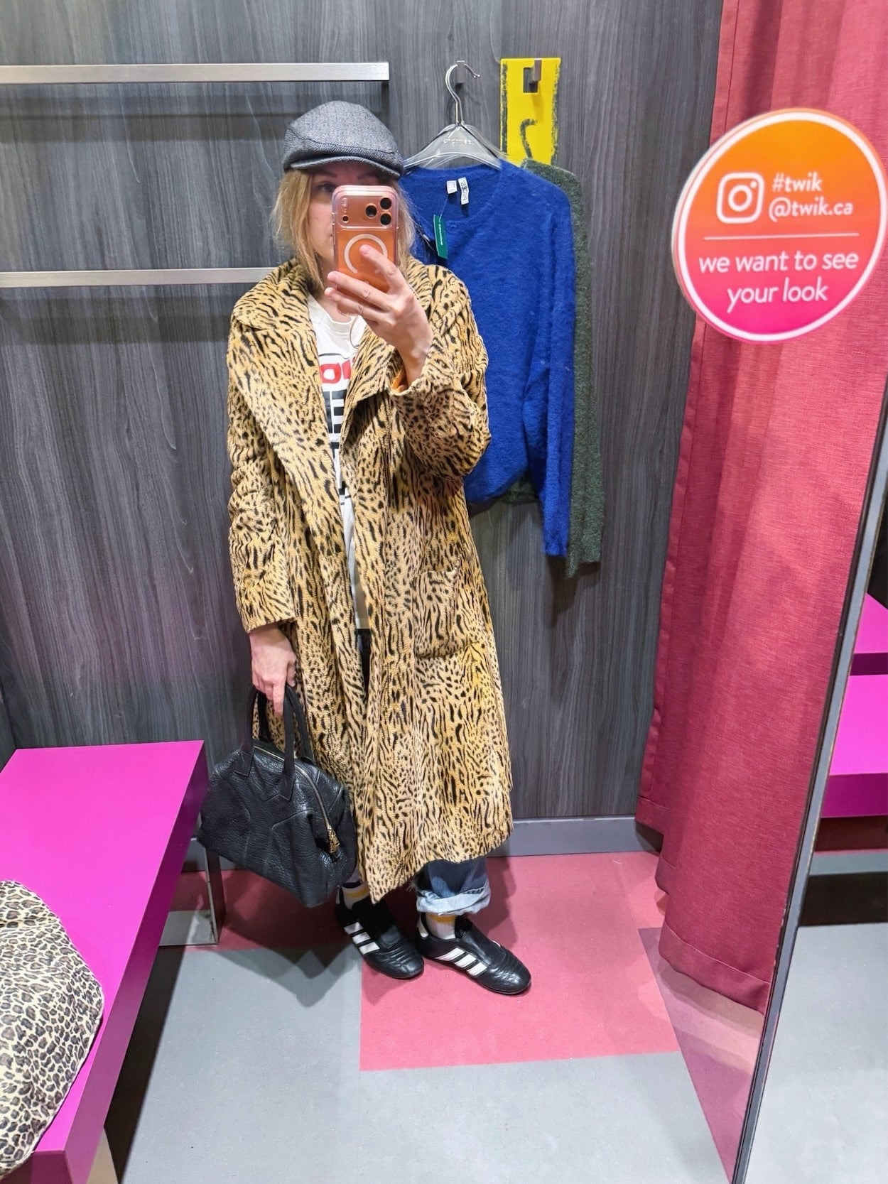 Sara of livelovesara is standing in front of a mirror taking a photo of her outfit. She is wearing a Vision Streetwear t-shirt with vintage Levis, a vintage animal print coat, grey herringbone cap, black Adidas, and a black YSL Easy bag.
